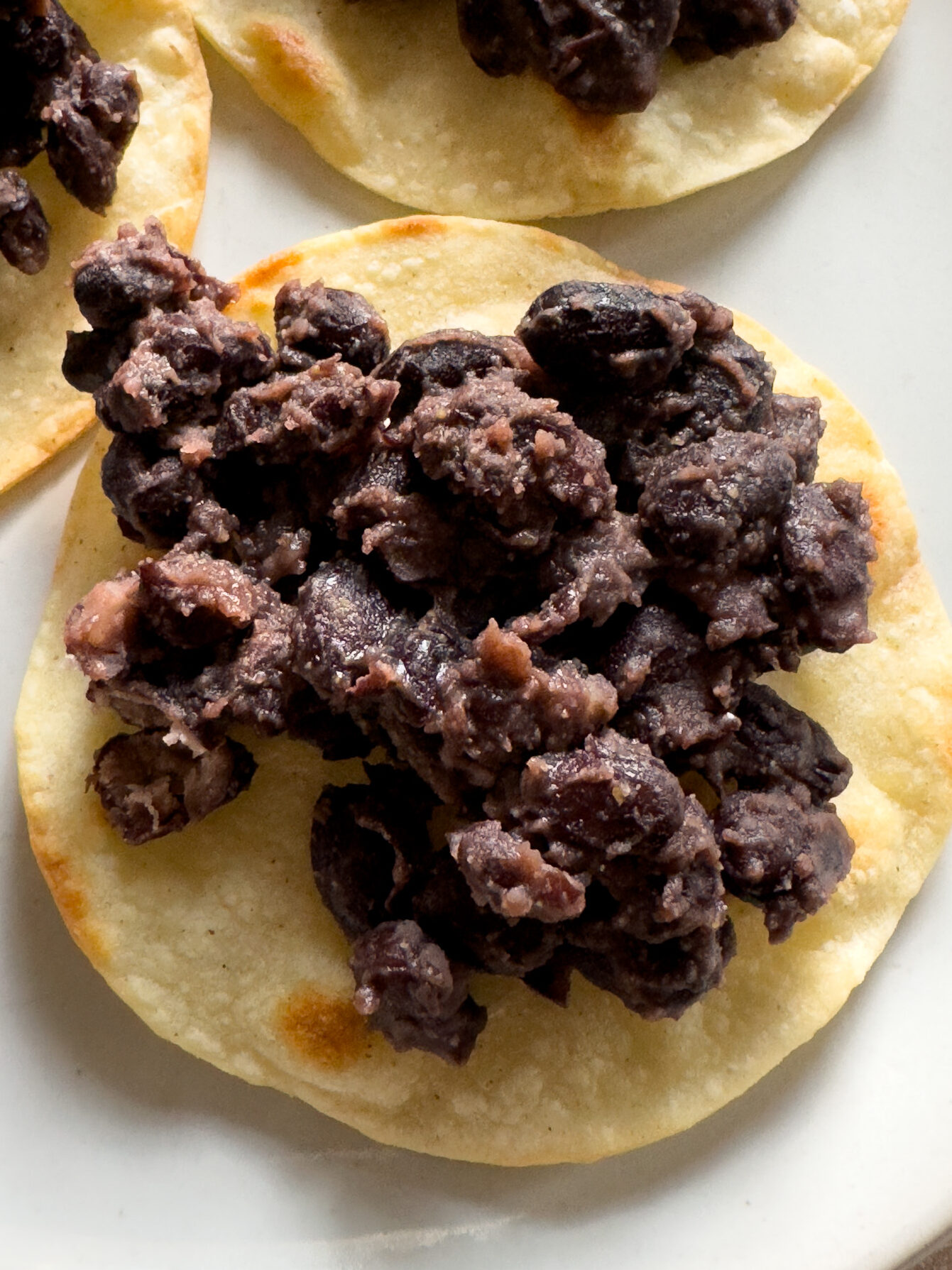 Spoon black beans on tostada