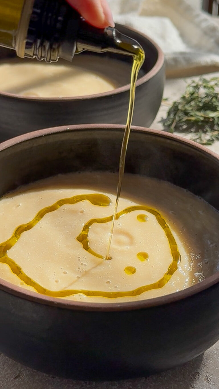 olive oil being drizzled over a white bean soup