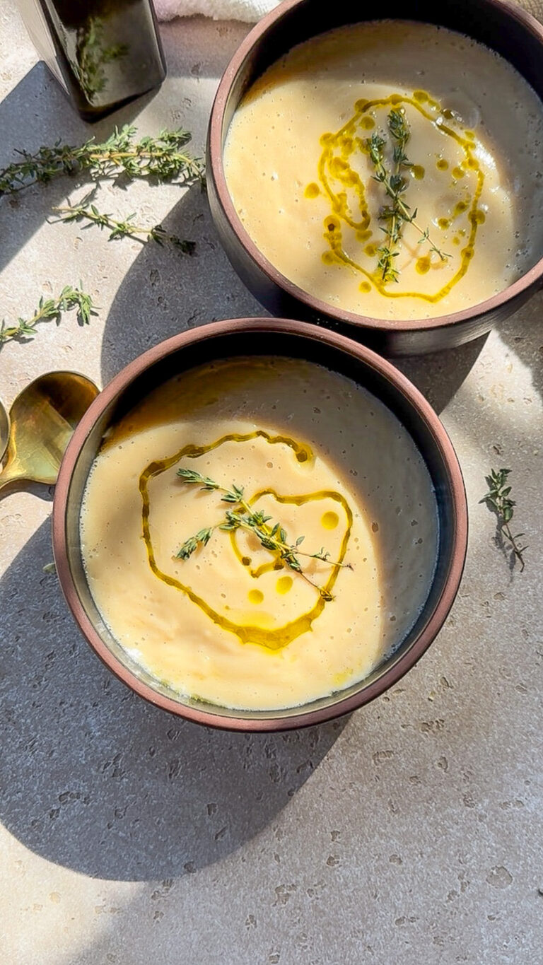 two bowls of a creamy white bean soup on a poured concrete counter.