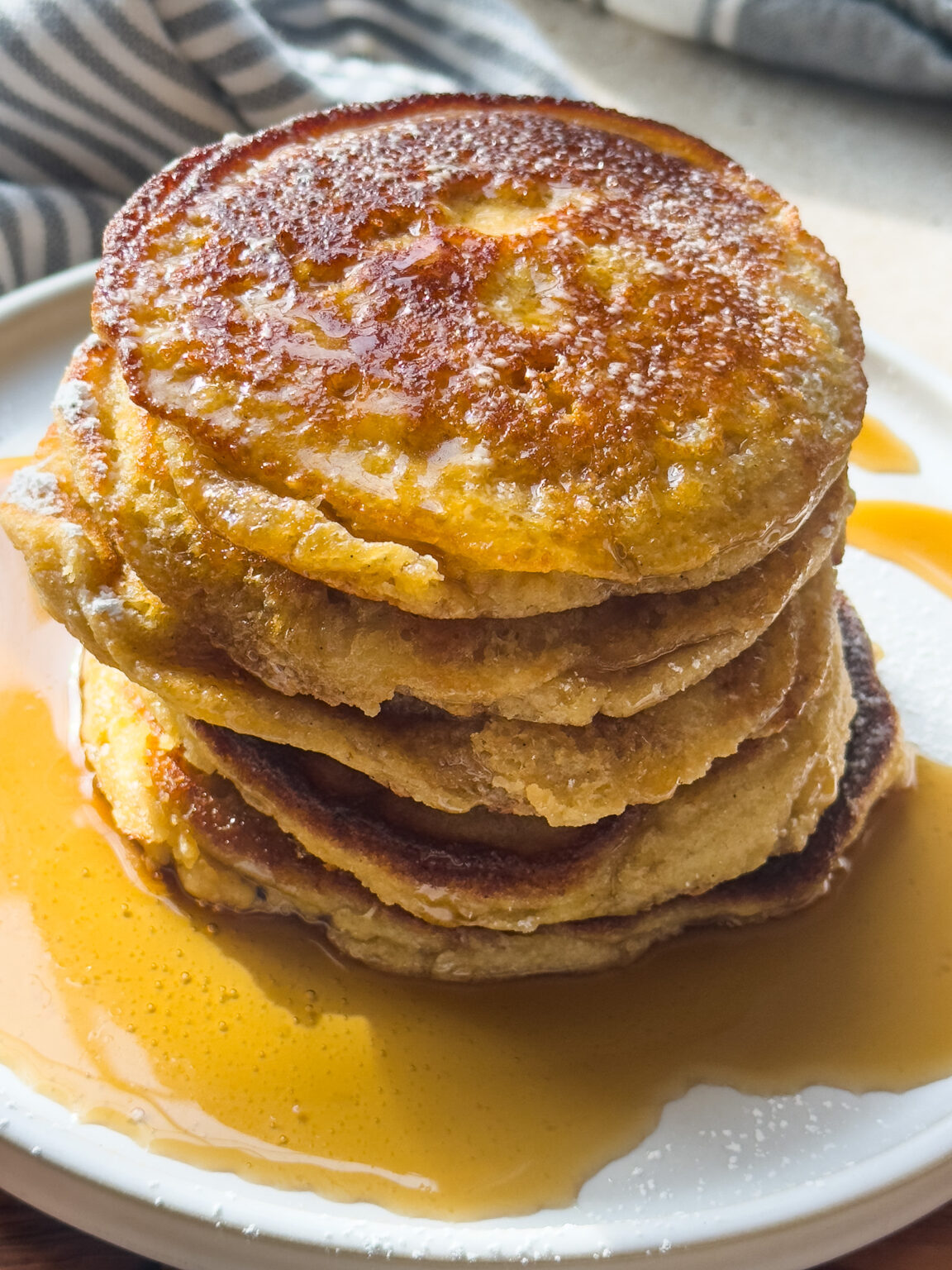 stack of gluten free pancakes on a white plate with maple syrup
