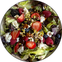 bowl of salad with feta, greens, blueberries and sliced strawberries
