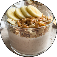 glass cup filled with pudding, bananas and a caramel drizzle